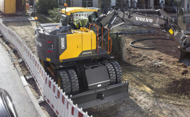 Volvo wheeled excavator digging trenches in a residential area in utilities.