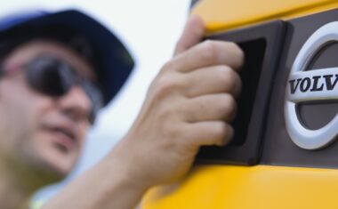 Close up of a man opening a service compartment on a Volvo heavy equipment machine.