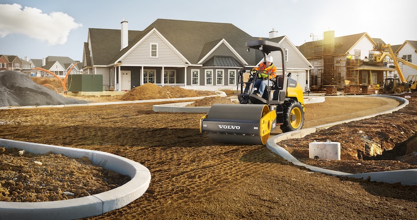 Volvo soil compactor compacting dirt for a new home’s driveway in residential construction.