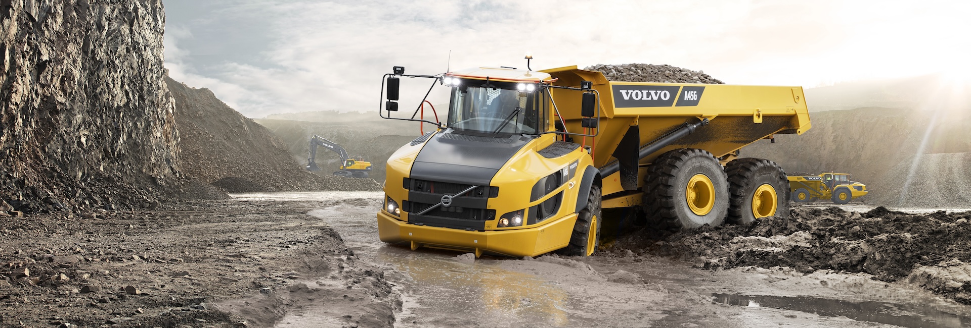 A Volvo A45G articulated hauler driving through deep, wet mud.