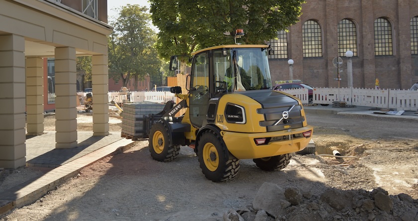 A Volvo L20 Electric wheel loader hauling landscaping pavers on a construction jobsite.